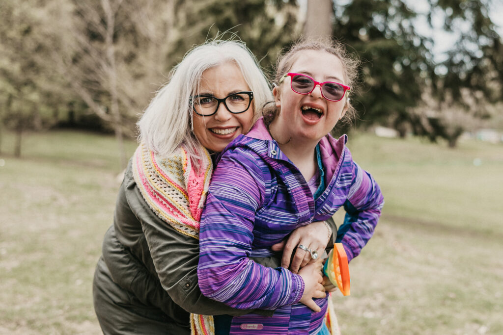 Mother and Daughter hugging and smiling outside at a park